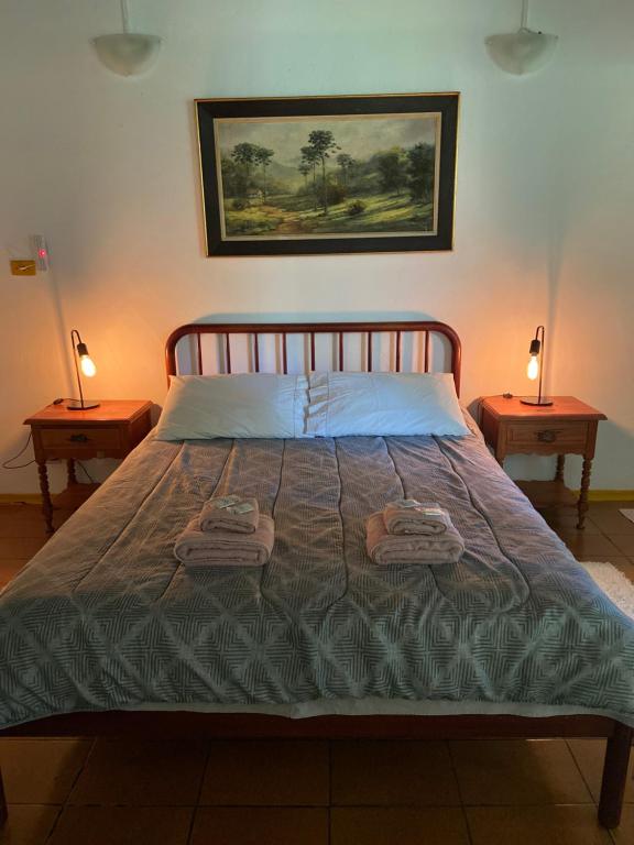 圣弗朗西斯科泽维尔Chalés SFX的一间卧室配有一张床,两台桌子上放着两盏灯