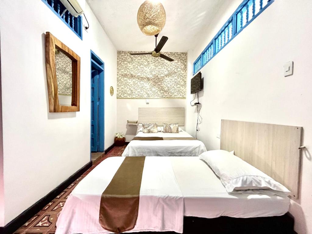 圣玛尔塔Hotel Kasaya Real的白色墙壁客房的两张床