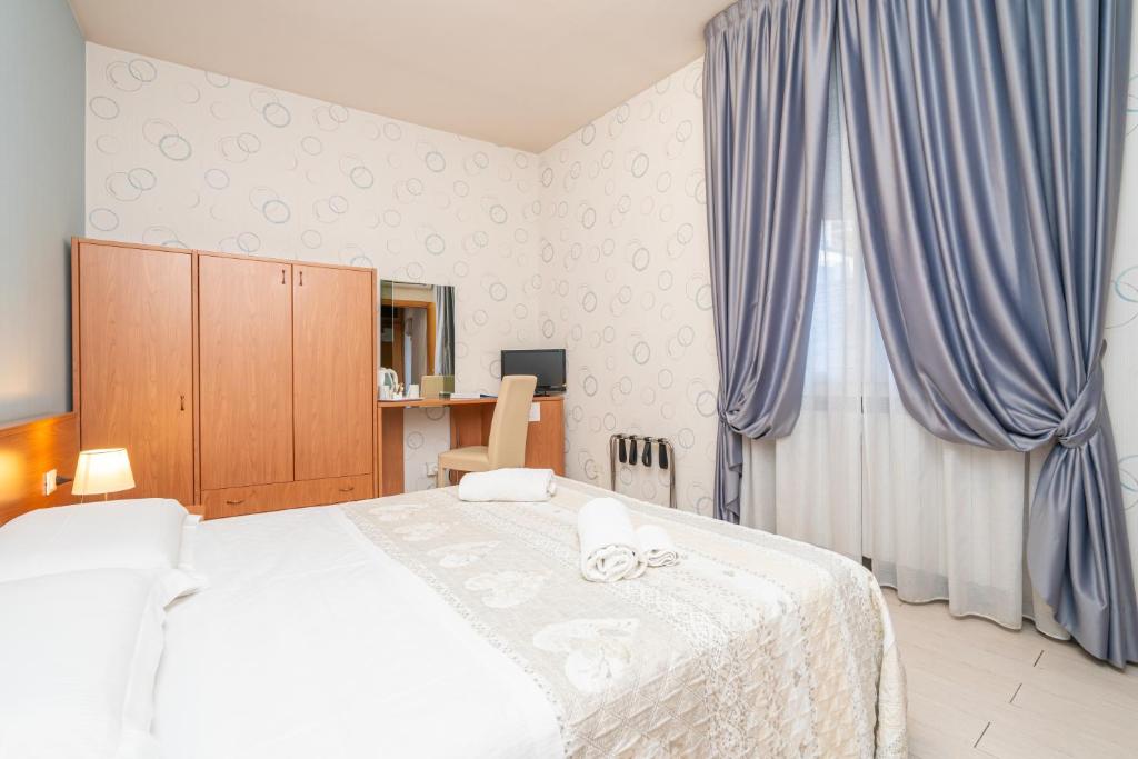 博洛尼亚多纳泰罗酒店的一间卧室配有一张蓝色窗帘的大床
