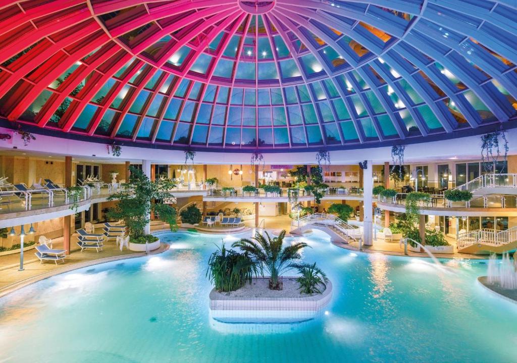 沙博伊茨格兰贝尔费德尔酒店的一座大型室内游泳池,位于一座拥有圆顶天花板的建筑中