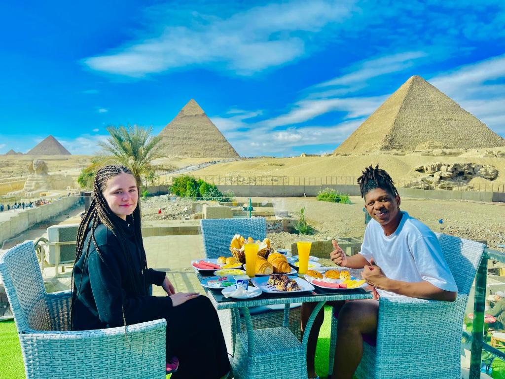 开罗Blue Scarab Pyramids View的坐在金字塔前桌边的男人和女人