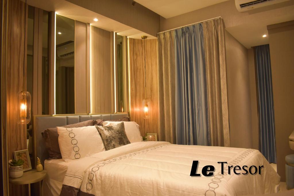 泗水Le Tresor Benson Apartment at Supermal Pakuwon的卧室配有白色的床和镜子