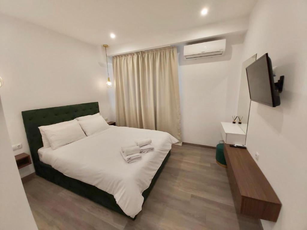 雅典Real City Suites Syntagma的卧室配有白色的床和电视。