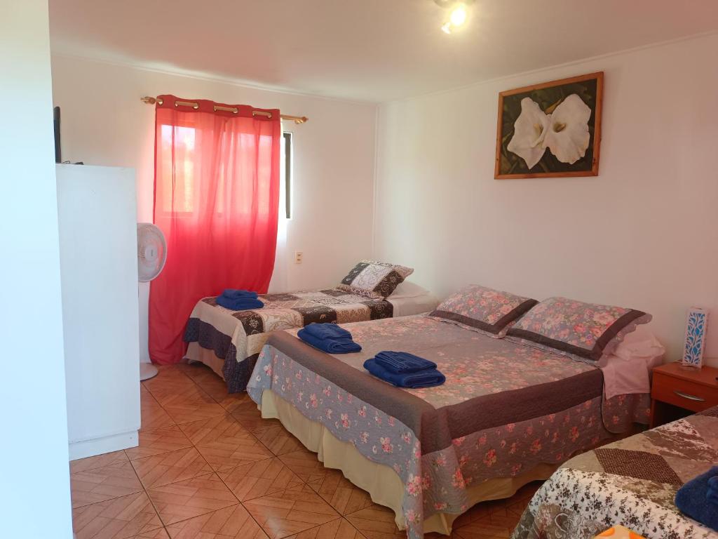 安加罗阿cabañas Te Pito Kura的一间设有三张床和红色窗帘的房间