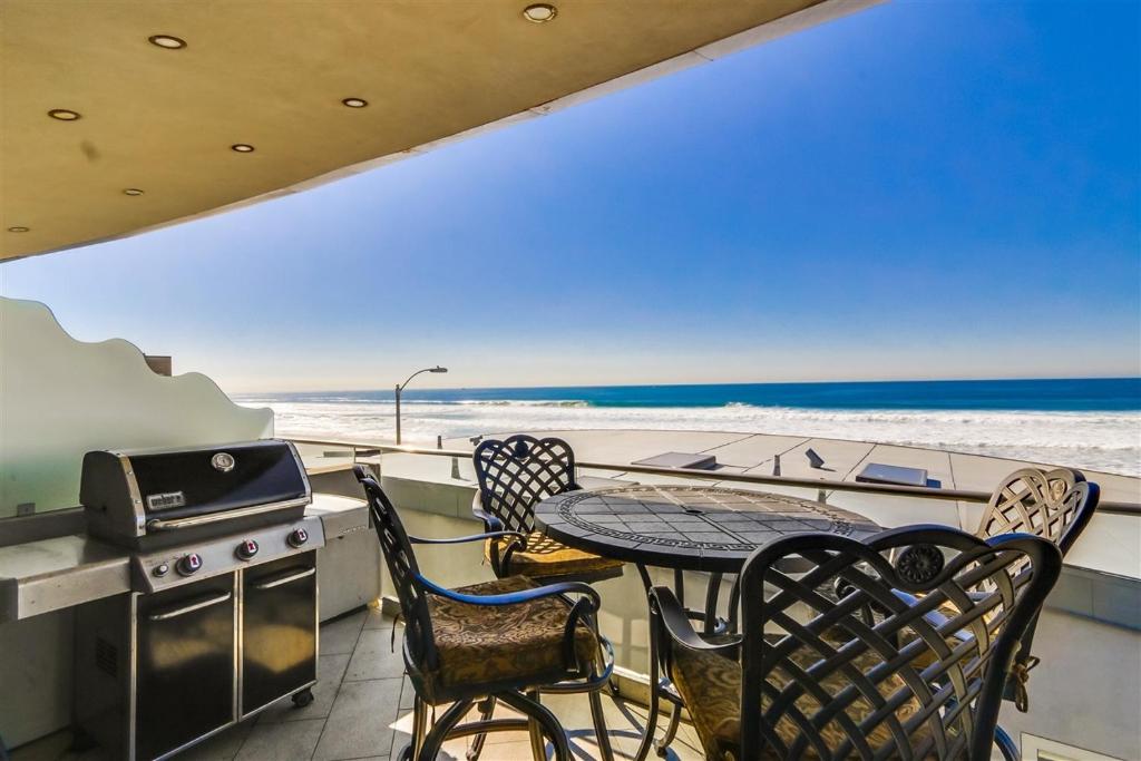 圣地亚哥Ocean view, two-level condo with stunning view, decks, fast WiFi & fireplace的一个带桌椅和海滩的阳台