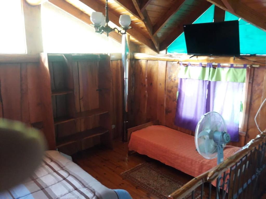 吉亚迪诺镇Cabaña villa giardino C.R的小屋内配有电视和床的房间