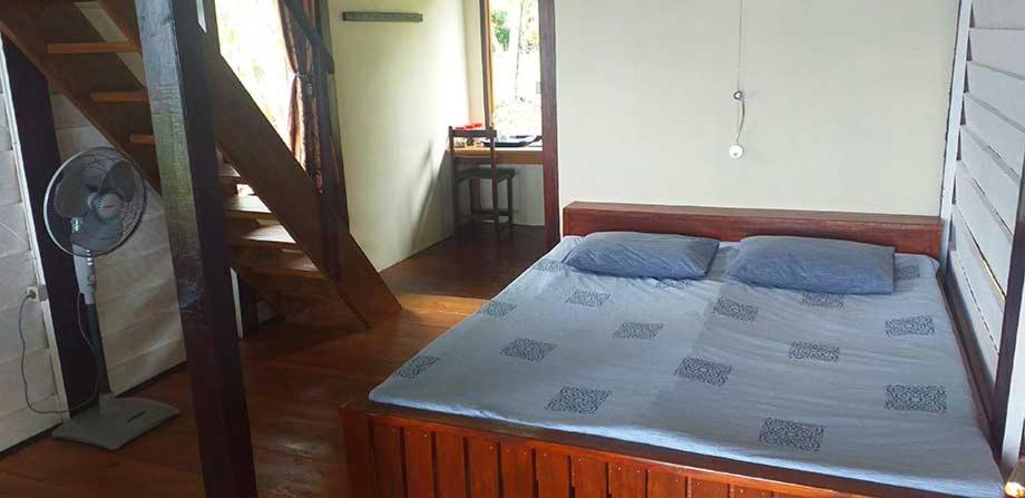 BenihaBogani-Cottages的一间卧室配有一张带蓝色枕头的床和风扇