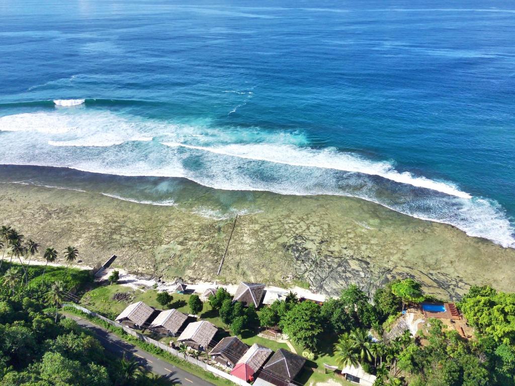 NaibosBatuRundung Surf Resort的享有海滩的空中景致,设有房屋和海洋