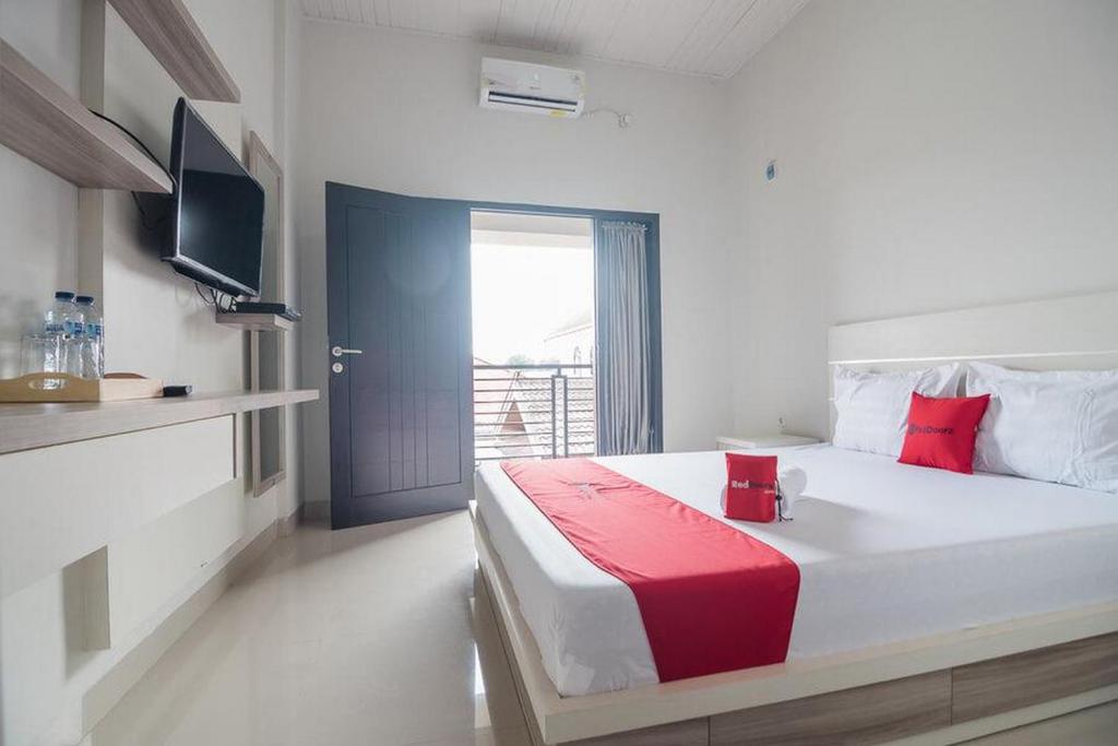 占碑市RedDoorz Syariah near Tugu Juang Jambi的一间卧室配有一张带红色毯子的大床