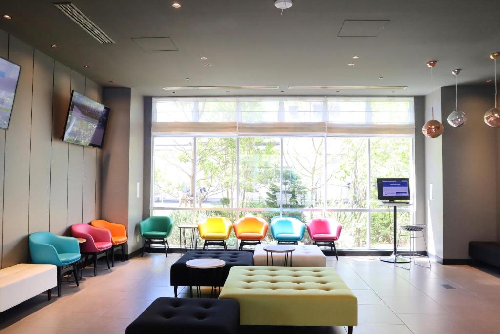 浦安东京湾宜必思尚品酒店的一间设有五颜六色椅子和大窗户的等候室