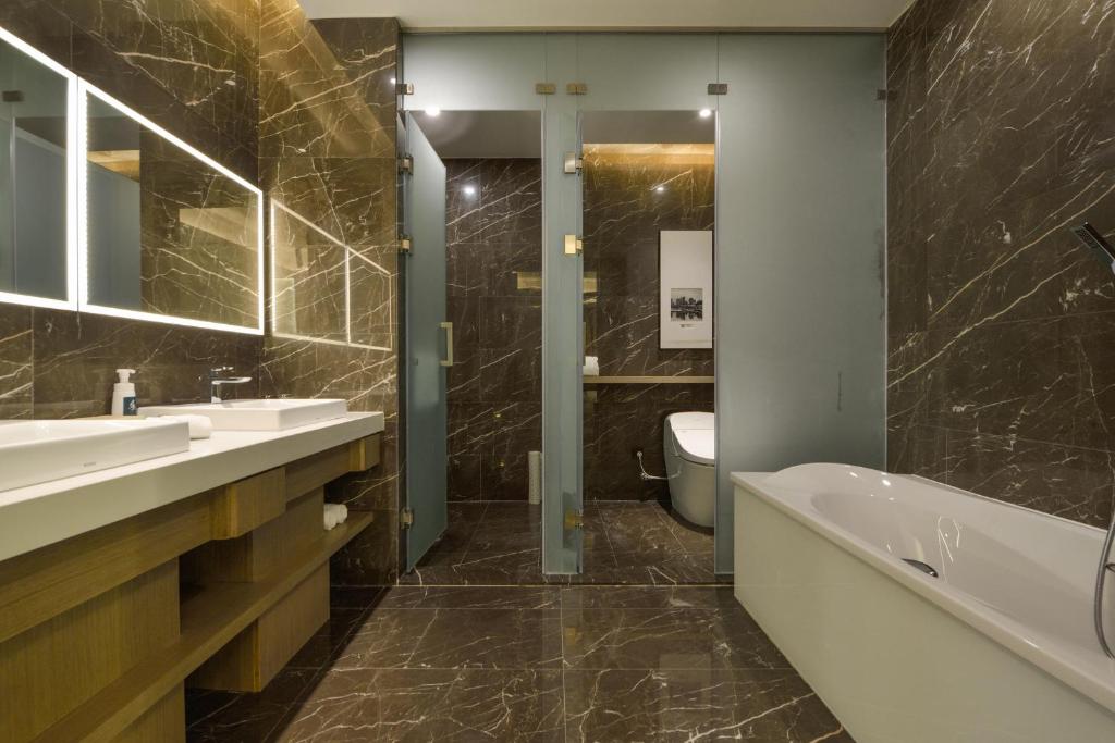 大连大连火车站亚朵酒店的一间带两个盥洗盆、浴缸和卫生间的浴室