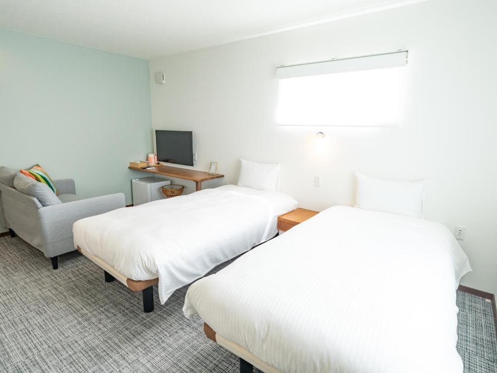 富良野AIR FURANO的酒店客房,配有两张床和椅子