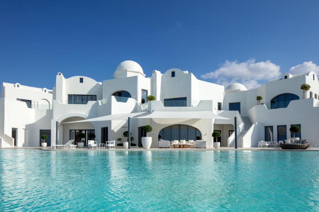 Al RahbaAnantara Santorini Abu Dhabi Retreat-Adults Only的一座白色的大建筑,前面设有一个游泳池
