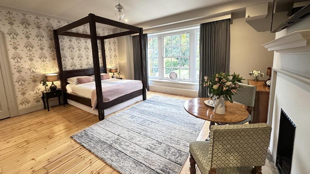 温坎顿Holbrook Manor & Spa - OCEANA COLLECTION的一间带天蓬床和桌子的卧室以及一间带桌布的房间。
