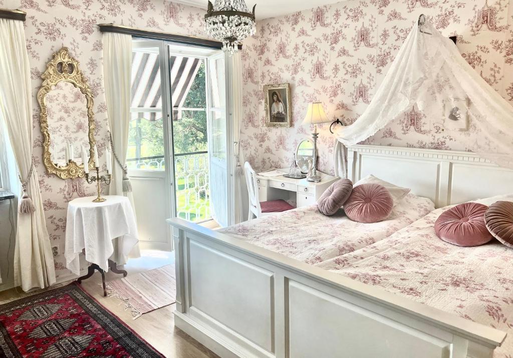 赛夫勒比勒鲁德别墅酒店的卧室配有白色的床铺和粉红色的壁纸