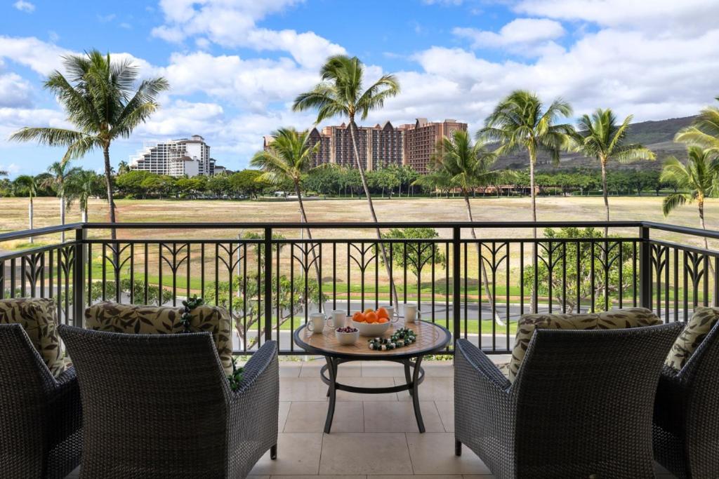 卡波雷Ko Olina Beach Villas O414的阳台配有桌椅和棕榈树。