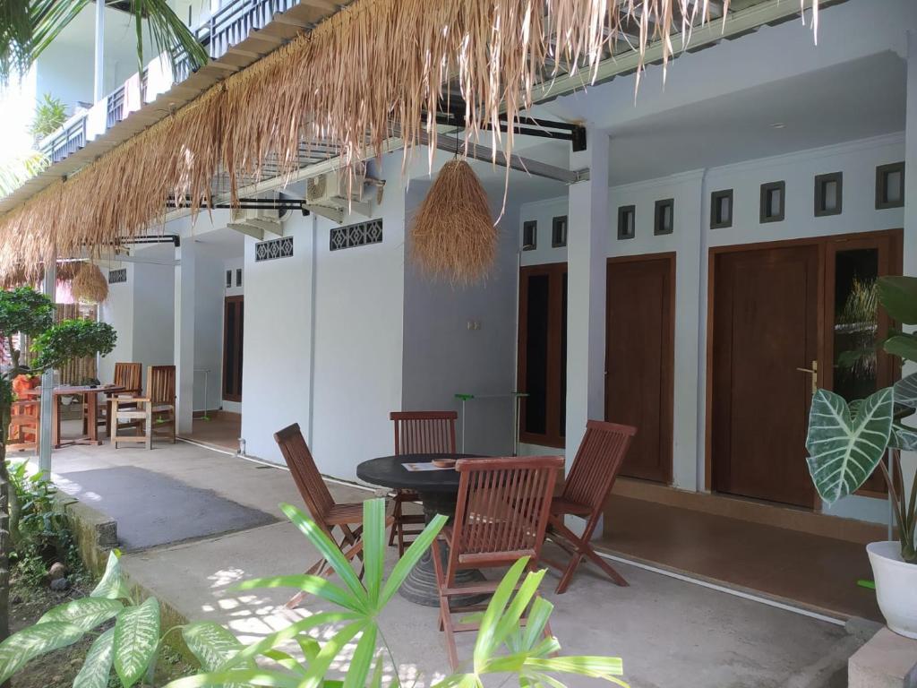 龙目岛库塔Merendeng Hostel Kuta的房屋的庭院,配有桌椅