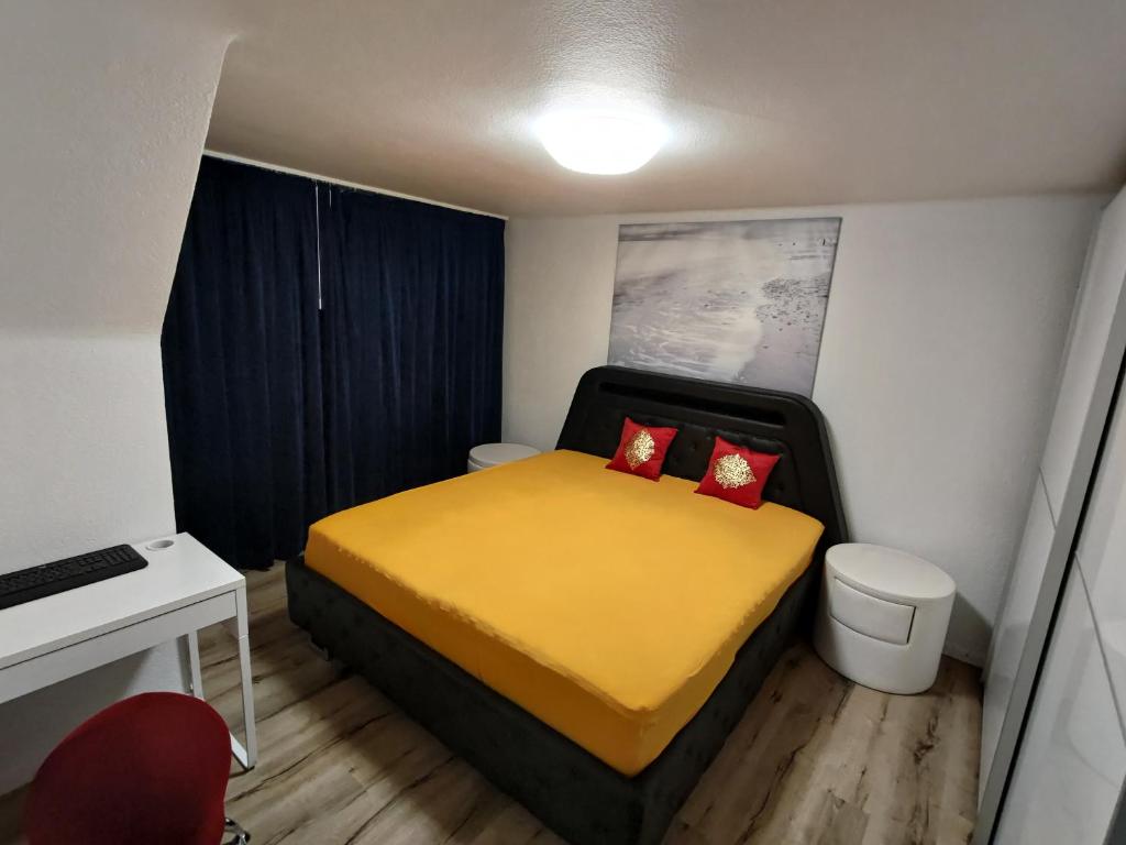 特林巴赫Butthouse Apartments的一间小卧室,配有黄色的床和红色枕头