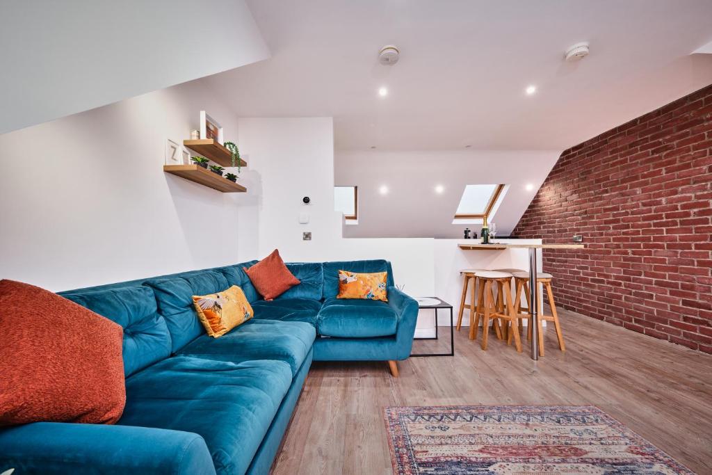 斯图尔特港Portstewart Central Loft Apartment的客厅设有蓝色的沙发和砖墙