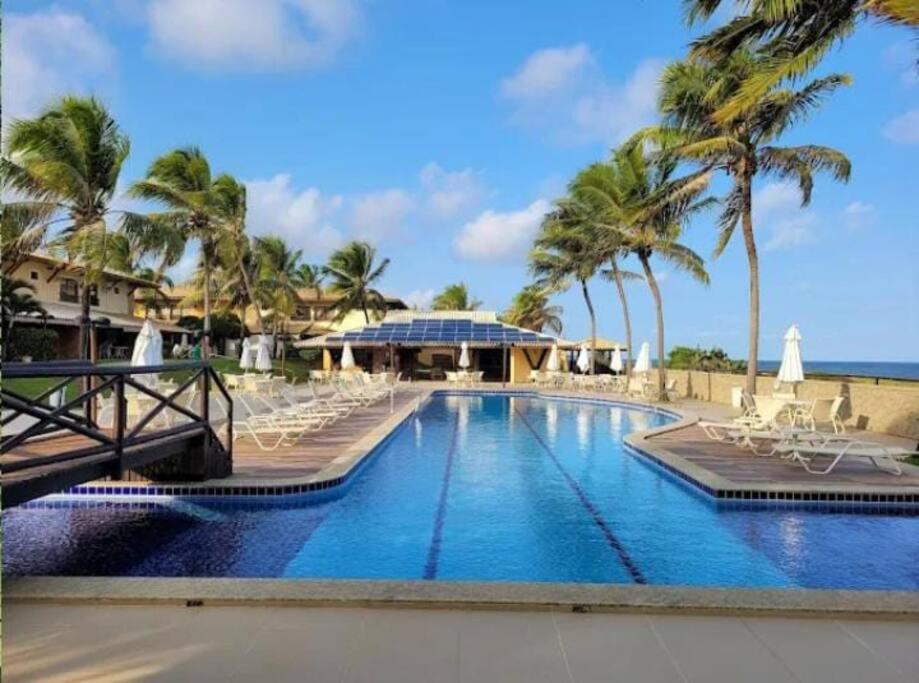 CamassariItacimirim Villas da Praia的度假村的游泳池,配有椅子和棕榈树