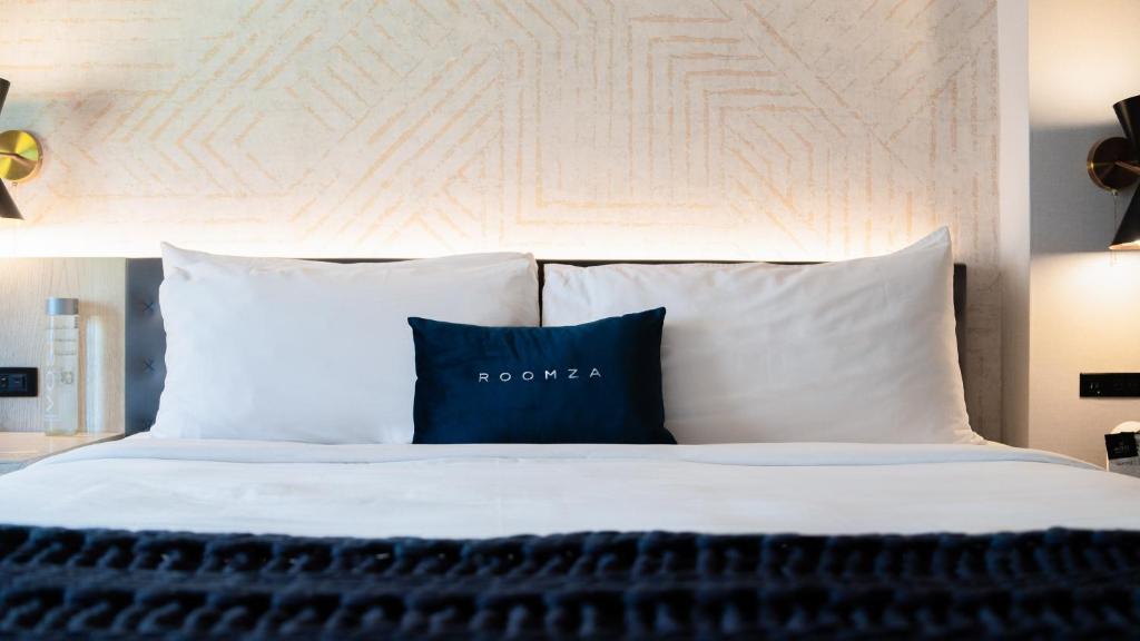 纽约Roomza Times Square at Pestana CR7的一张带白色床单和蓝色枕头的床
