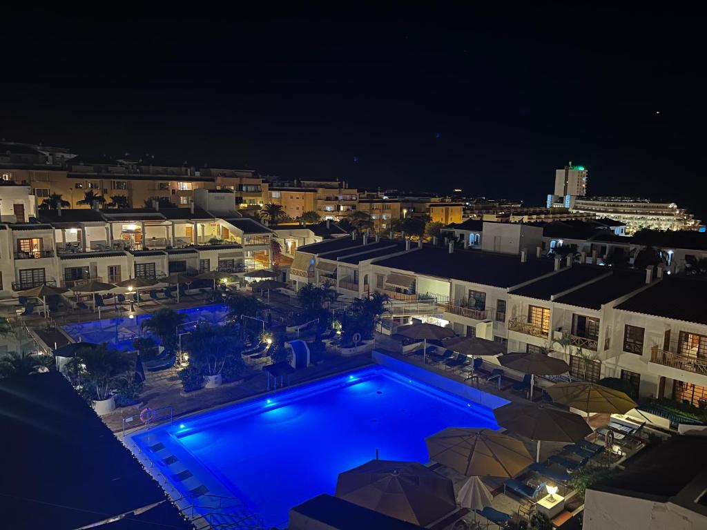 阿罗纳Atlantic View Apartment Los Cristianos At Marysol Hotel Tenerife的城市的游泳池,晚上有蓝色的灯光