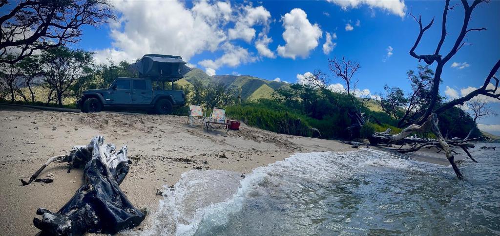 帕依亚Embark on a journey through Maui with Aloha Glamp's jeep and rooftop tent allows you to discover diverse campgrounds, unveiling the island's beauty from unique perspectives each day的停在沙滩上的蓝色卡车