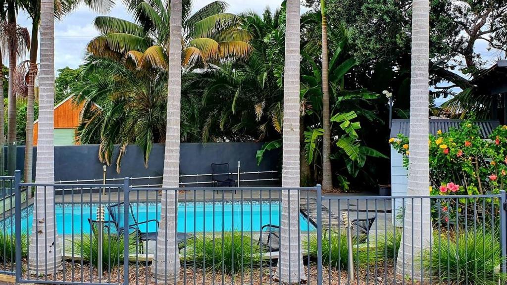 拉塞尔Stay n Play n Russell的游泳池前带椅子和棕榈树的围栏
