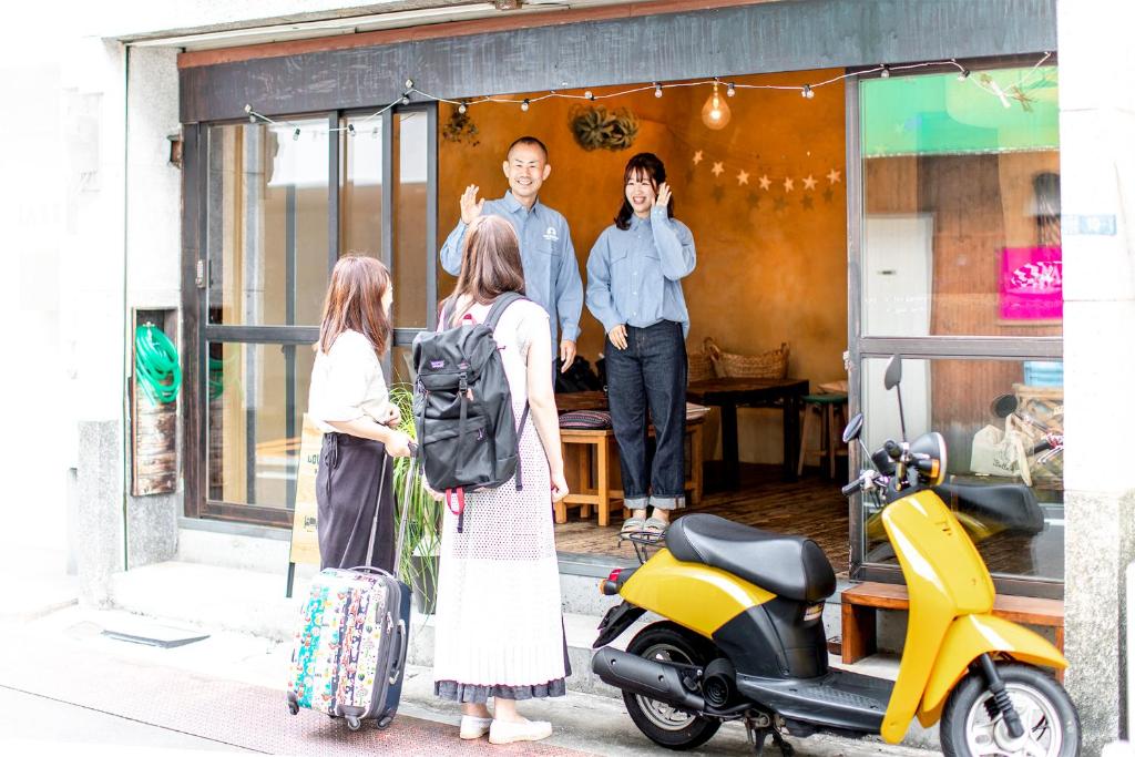东京LovesunshineBackpackers的一群人站在商店外面,拿着一辆小摩托车