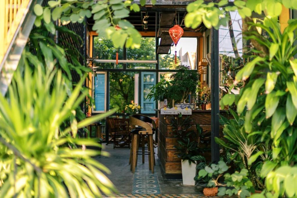 Ðông Tác (1)Trại Hoa Vàng Homestay at Tuy Hòa Phú Yên的一间种有植物的餐厅,配有桌椅