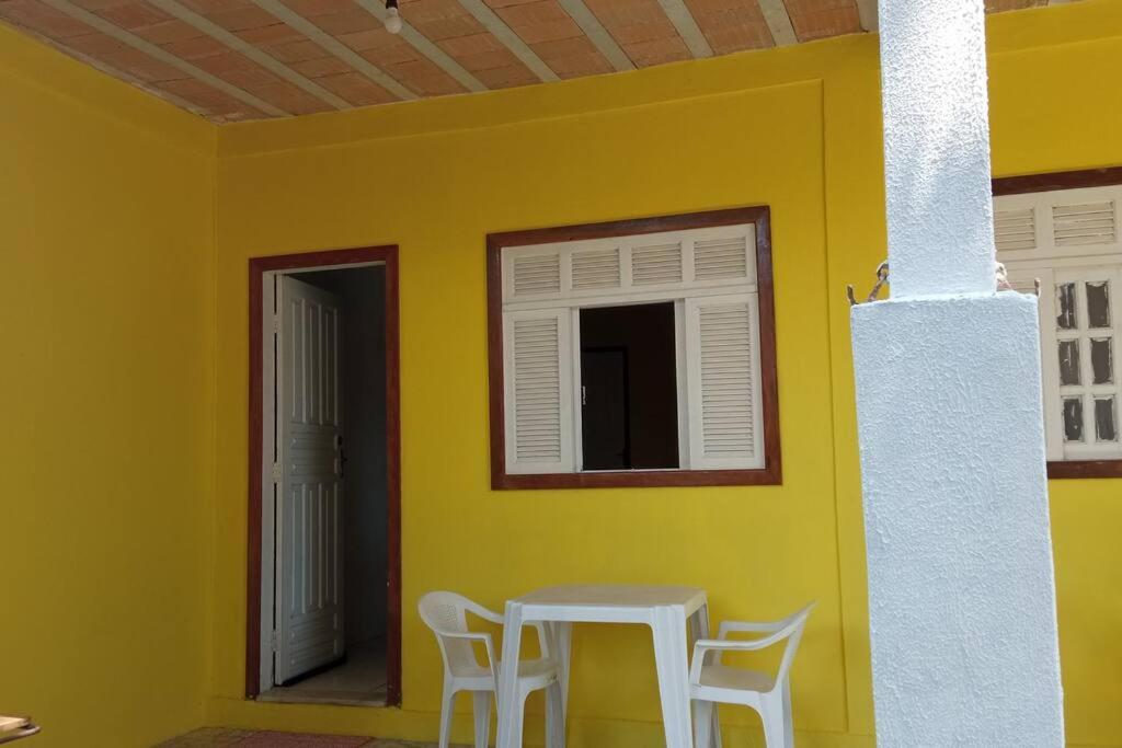 库穆鲁沙蒂巴Suíte em Cumuruxatiba beira-mar的客房内的黄色墙面,配有桌椅