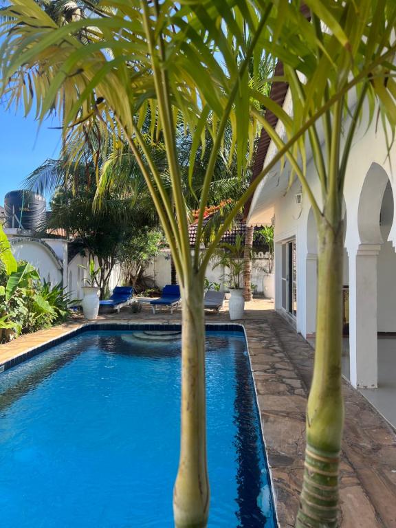 帕杰UKAYA VILLA的一座房子旁的游泳池,两棵棕榈树