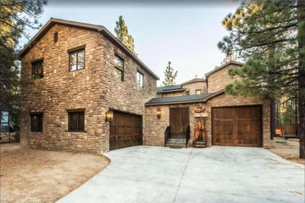 大熊湖Big Bear Castle by AvantStay Private Home in Great Big Bear Location w Hot Tub的砖屋,设有车库和车道