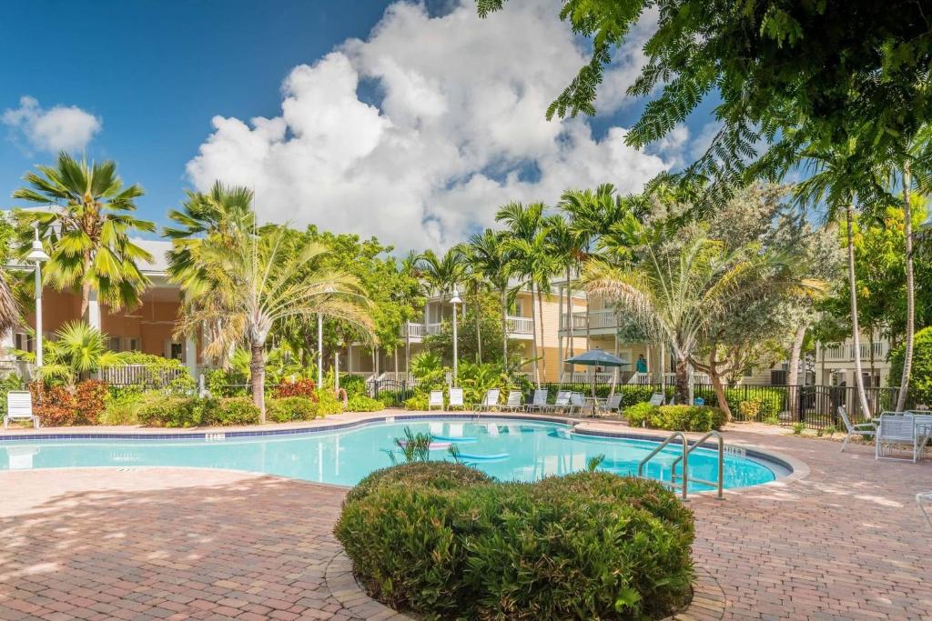 斯托克岛Coral Palm by AvantStay Key West Walkable Gated Community Shared Pool Month Long Stays Only的一座楼前棕榈树游泳池