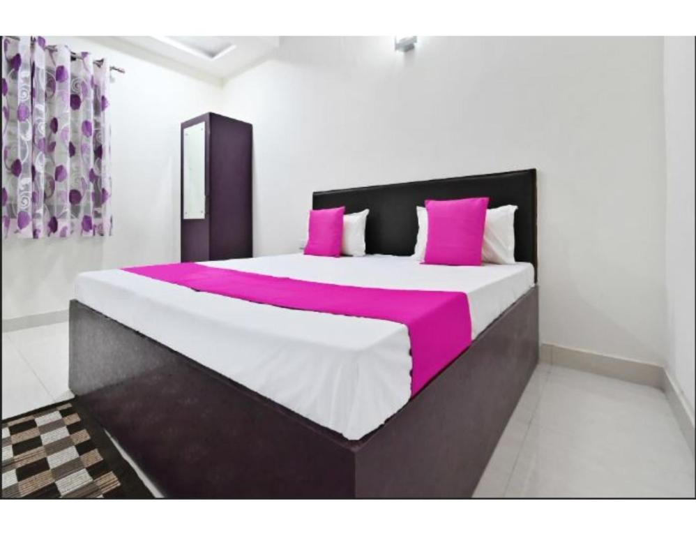 阿格拉Hotel Raj Inn, Agra的一间卧室配有一张大床,铺有粉色和白色的床单。