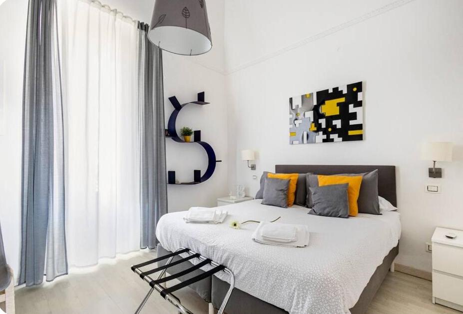 卡普尔索Casa dei nonni的白色卧室配有带橙色枕头的大床