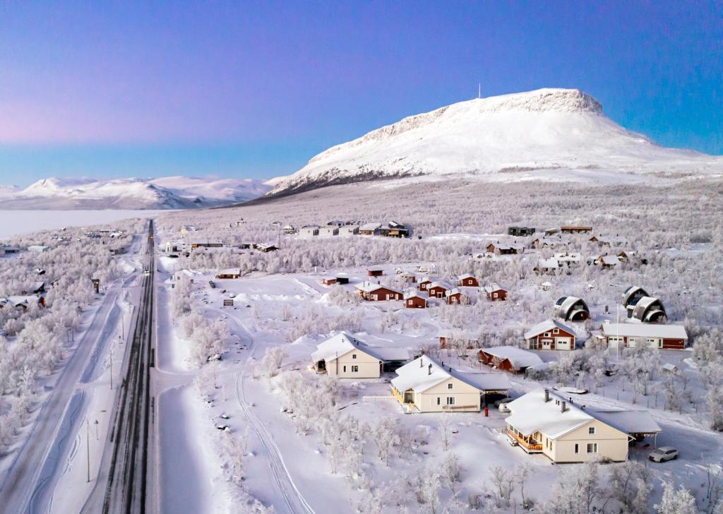 基尔匹斯扎我维Aurora Apartment Kilpisjärvi的被雪覆盖的村庄,背景是山