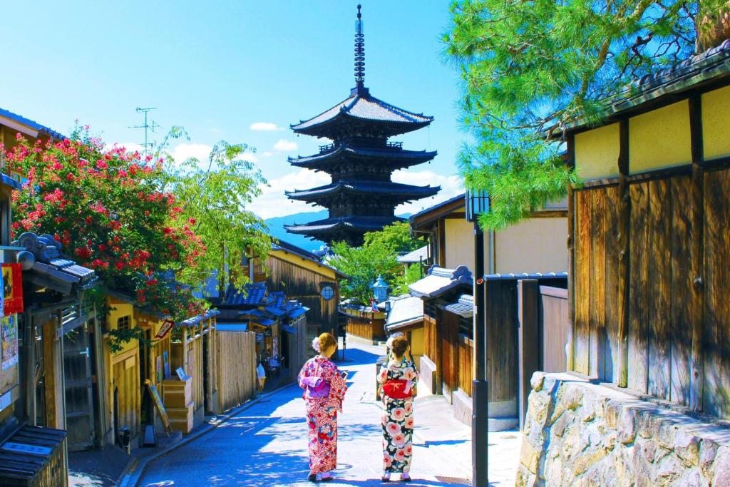京都纯和风料理旅馆Kinoe的两个和服上的女人在一条带有宝塔的街道上走着
