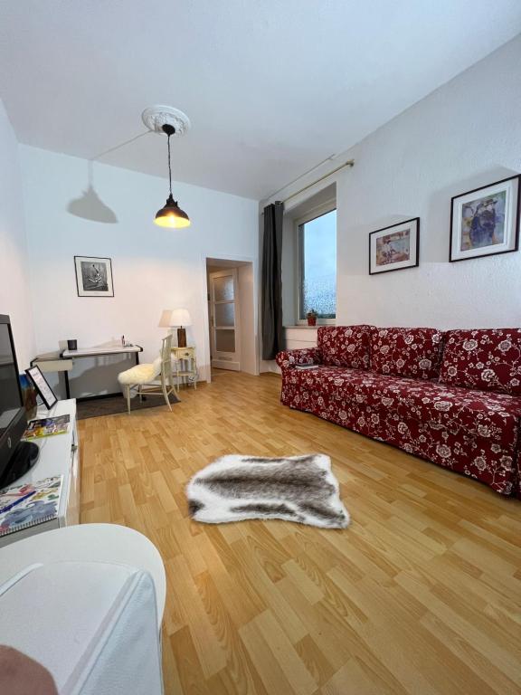 杜伊斯堡Casa Estrella的客厅铺有木地板,配有红色沙发
