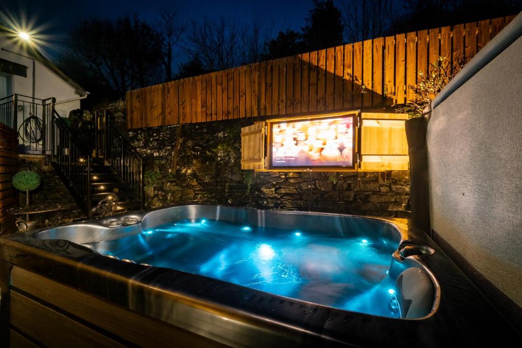 鲍内斯温德米尔Stunning cottage Grade 2 listed with parking and Hot Tub的晚上在后院的按摩浴缸