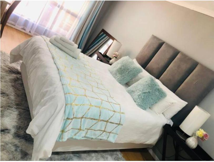 伯诺尼Serenity Cottage的一间卧室配有带白色床单和蓝色枕头的床。