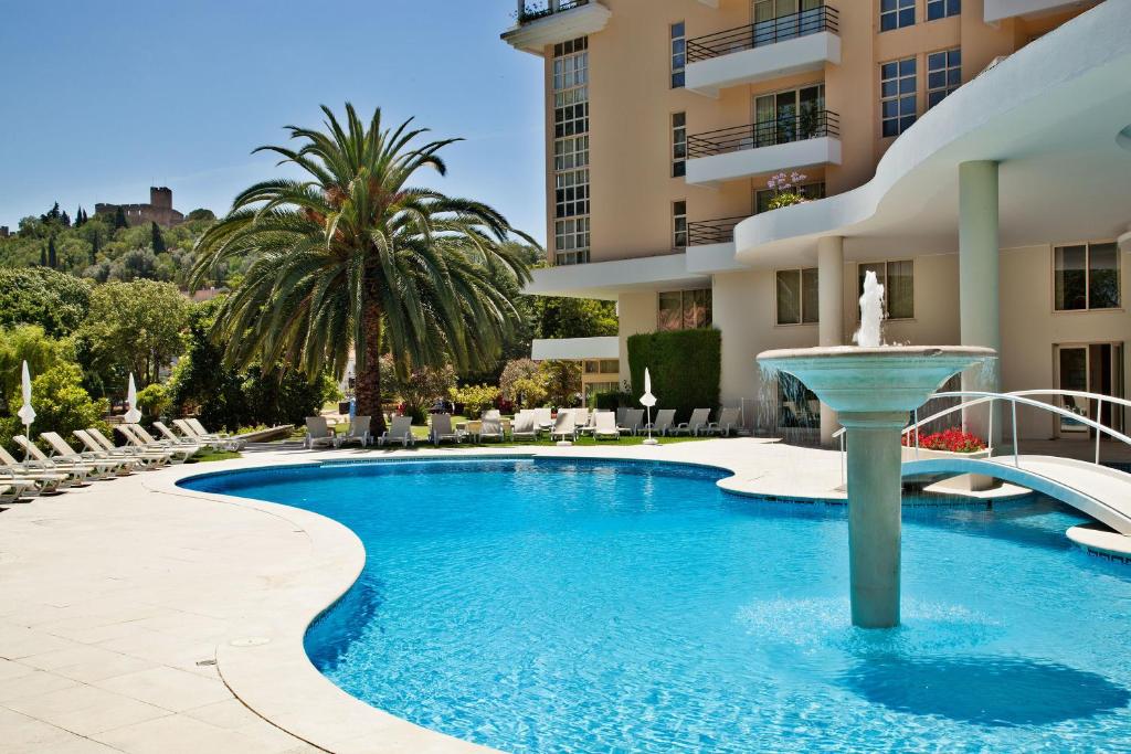 托马尔多斯丁帕鲁司酒店的一座大楼前的游泳池,带喷泉