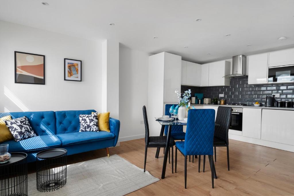 BuckinghamshireLivestay-Modern Apartments Building in Aylesbury的客厅配有蓝色的沙发、桌子和椅子