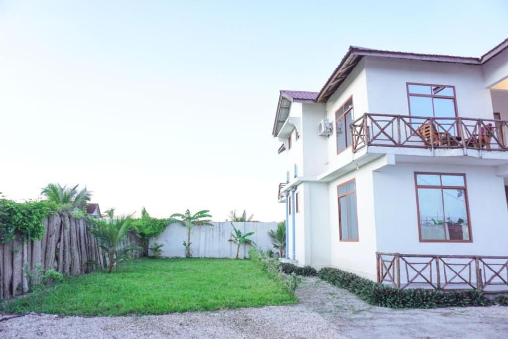 吉汶瓦Asili Nyumbani Residence的白色的房子,有栅栏和院子