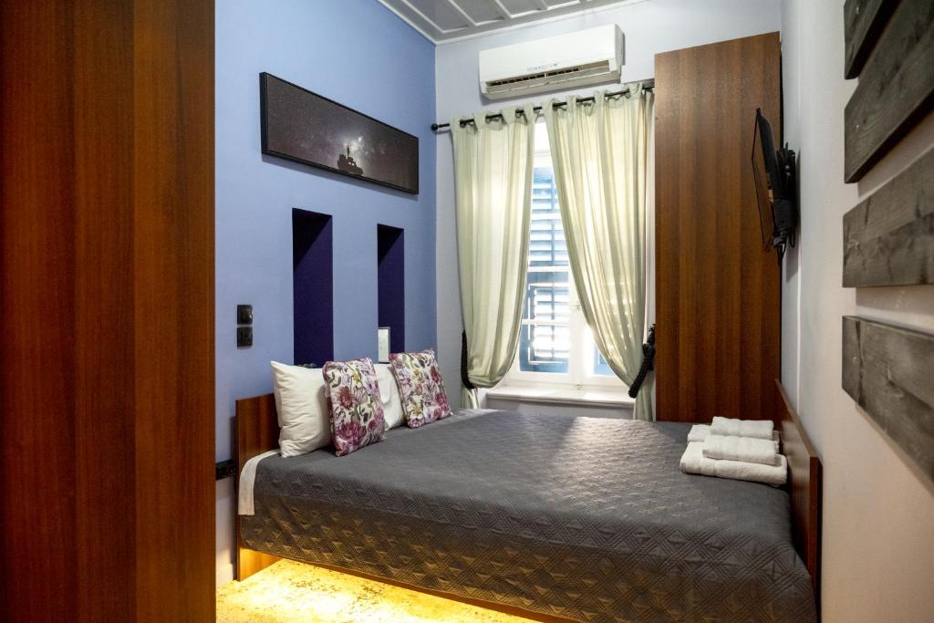 纳夫普利翁Deisisroom nafplio Afroditi的一间卧室配有一张蓝色墙壁的床和一扇窗户