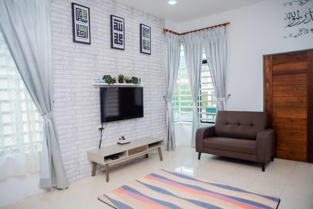 关丹CikJah Guest House SEMI-D的客厅配有沙发、电视和椅子