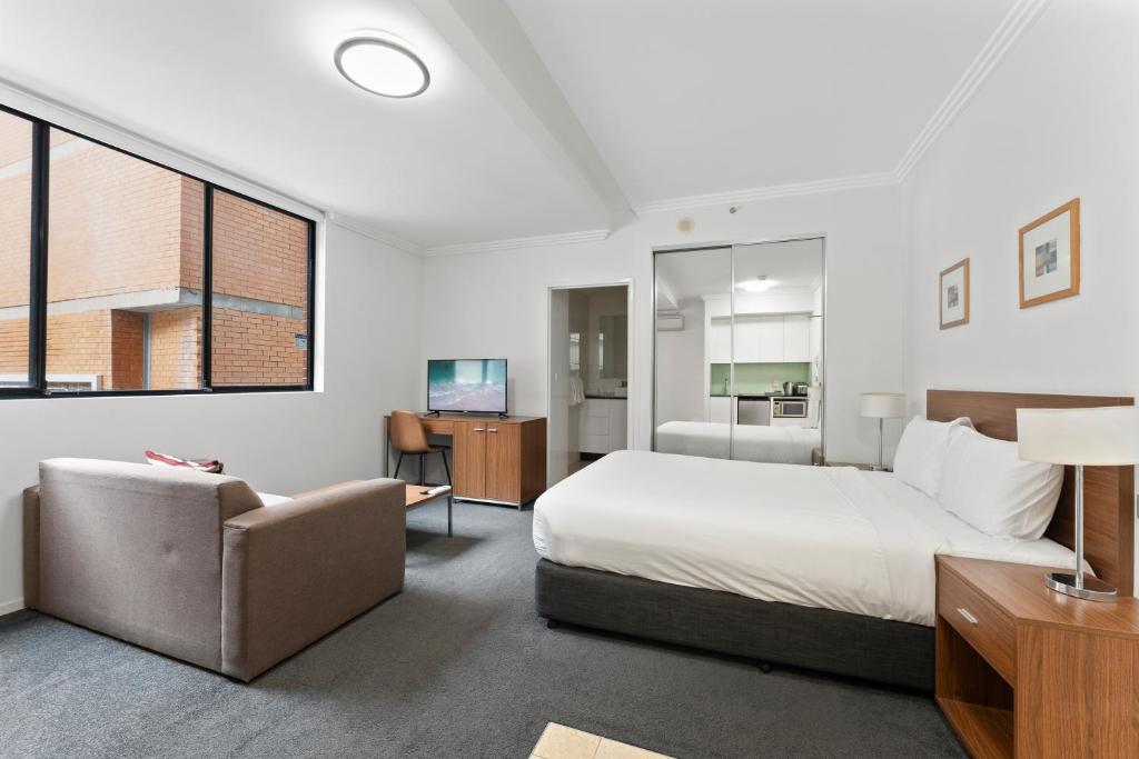 悉尼达令港APX公寓式酒店的一间卧室配有一张床、一张沙发和一台电视