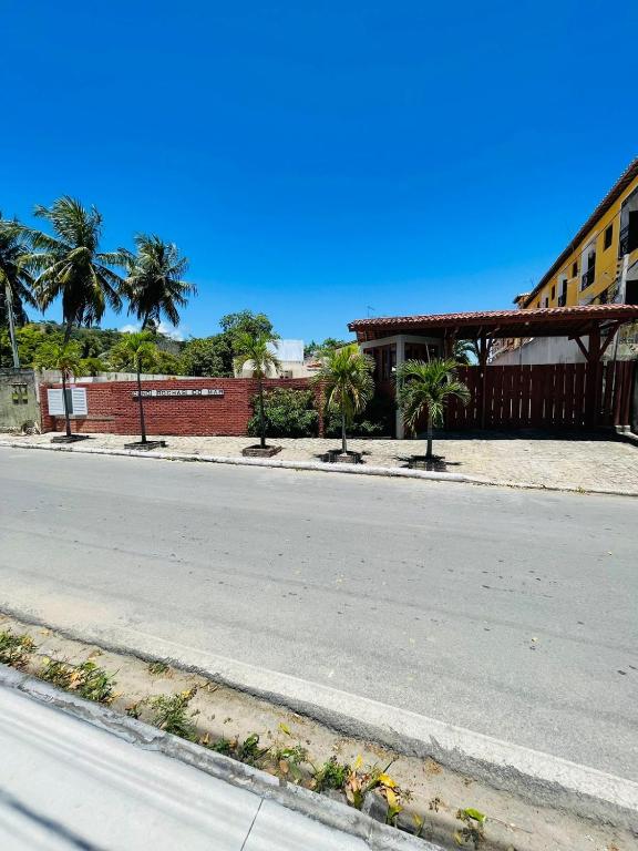 拉巴拉德纳圣米格尔Condomínio Rochas do Mar的棕榈树建筑前的一条空街道