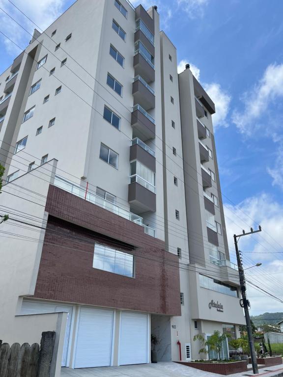 纳韦甘蒂斯Residencial Atalaia - Praia do Gravatá - Beto Carrero World的砖墙高大的白色建筑
