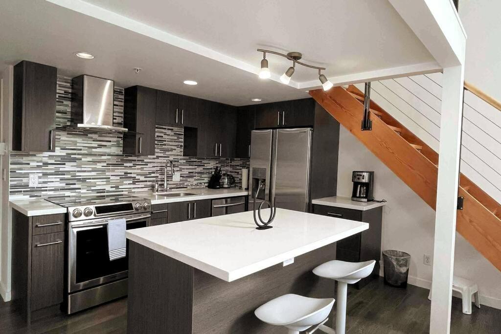 温哥华Modern top-floor 1-bedroom loft with free parking的一间厨房,在房间内配有白色的台面
